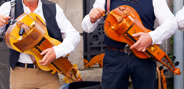 Senior men standing, playing the hurdy gurdy, close-up view. Lugo city, Galicia, Spain during San Froilán autumn traditional celebrations.