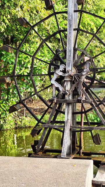 Vertical footage of a classic water turbine creating oxygen in a natural pond in a public park, Chiang Mai, Thailand.