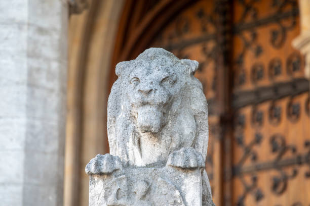 A striking stone lion statue in Munich stands against a clear blue sky, symbolizing strength and authority in an urban architectural setting.