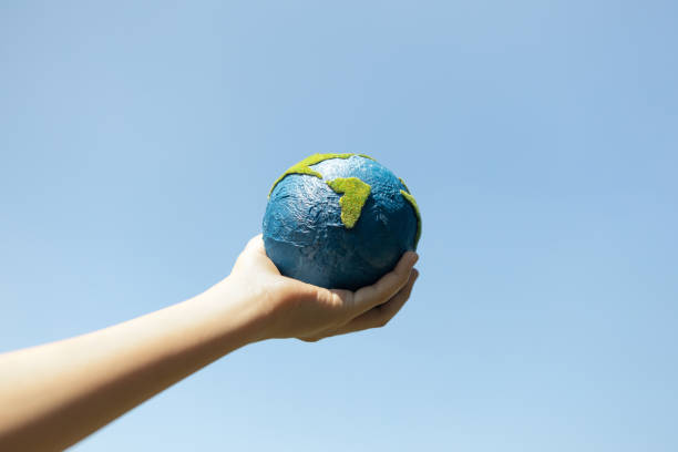 istock Young boy hand holding planet Earth globe with sky background. Gyre 2085510858