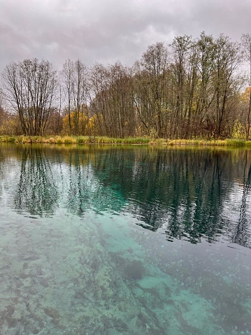 Lake in the forest with blue emerald water in cloudy weather in autumn. Kazan. Tatarstan. Trips. Adventures. Vacation. Hike. Walking route. Trees. Clouds. Ice water. Abyss. Cold. Damp. Beautiful. Hydrogen sulfide.