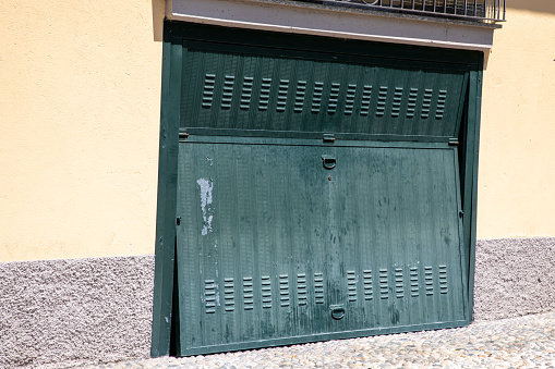 Old weathered and rusty steel door closed open green sequential metal door in building facade