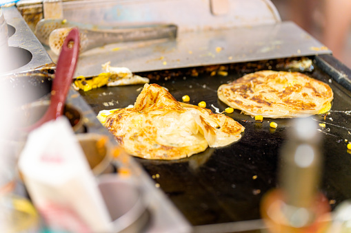Chef cooking Chinese style pancake selling to customers at street food night market near Ximen in Taipei, Taiwan. People enjoy and fun outdoor lifestyle nightlife travel, shopping and eating street food in the city on holiday vacation.