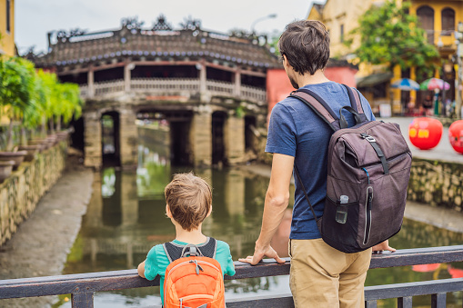 Father and son tourists on background of Beautiful Japanese Bridge in Hoi An. Vietnam. Vietnam opens to tourists again after quarantine Coronovirus COVID 19.