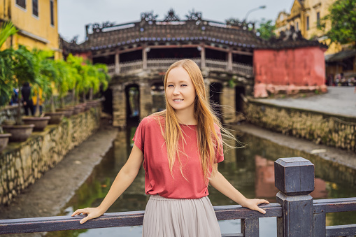 Woman tourist on background of Beautiful Japanese Bridge in Hoi An. Vietnam. Vietnam opens to tourists again after quarantine Coronovirus COVID 19.