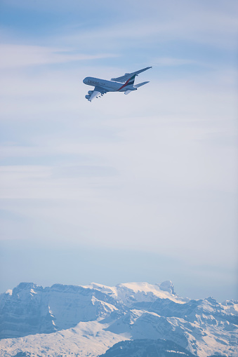 Emirates Airbus A380 departing Zurich Airport with some snow covered mountains in the background.