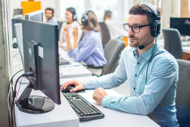 istock Focused middle aged handsome man in formal shirt and headset working on computer in call center agency. 2085620746