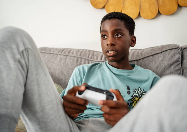 istock Boy playing a video game while sitting on a sofa at home 2085662514