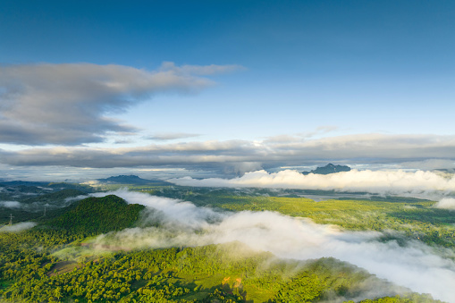 A stunning view of the sea of mist flowing down from the mountaintop. and covering the small village below, a drone's eye view. Above the sea of mist.