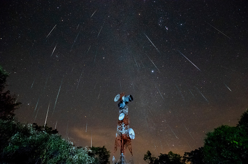 Long exposure night photography with star trails, meteor shower, and high mountain repeater station in Mae Mo District, Lampang Province, Thailand.