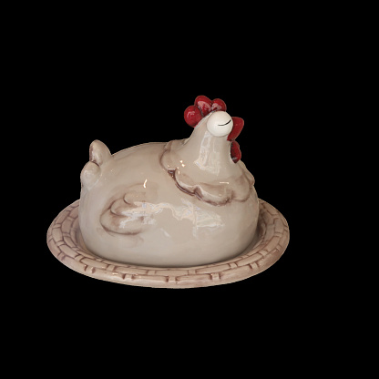 Charming ceramic butter dish shaped like a resting chicken, isolated on a black background