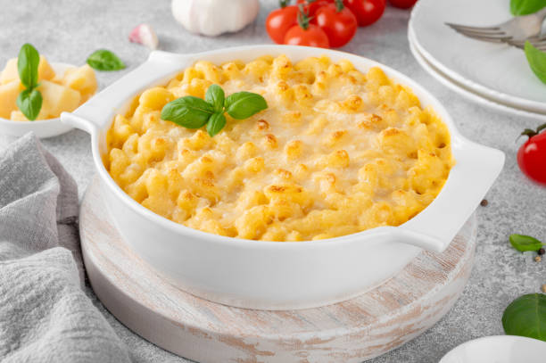 istock Mac and cheese in a white baking dish on a wooden board on a gray concrete background. American cuisine, comfort food. Copy space. 2085674336