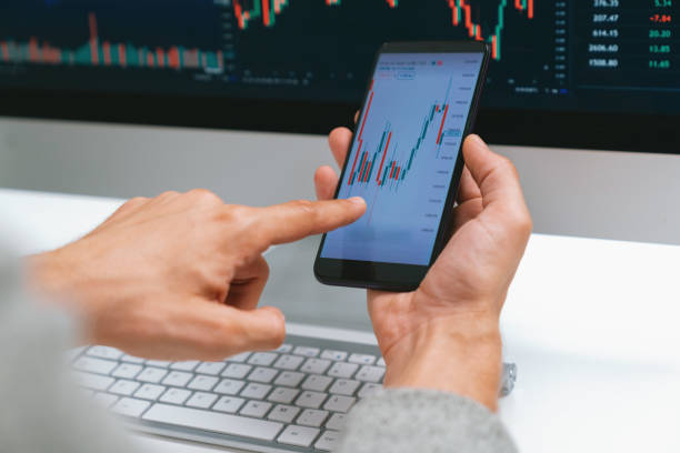istock Investors pointing on screen with smartphone with laptop in stock. Pecuniary. 2085684756