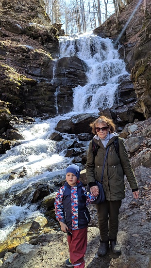 A high mountain rocky waterfall, a grandmother with her 5-year-old grandson.