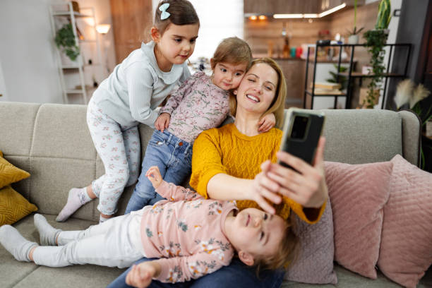 istock Mother and her three little daughters taking selfies at home 2085711859
