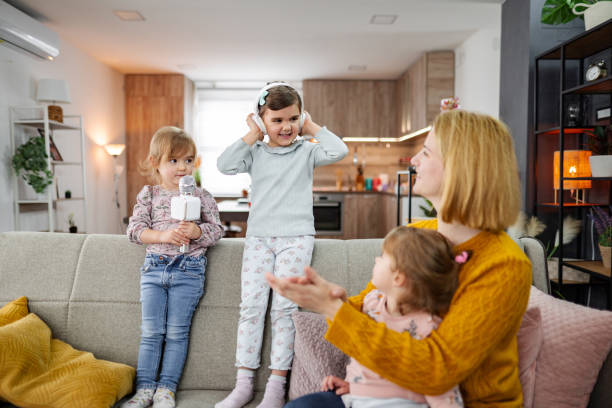 istock Loving mother with her three daughters playing with karaoke microphone  at home 2085712916