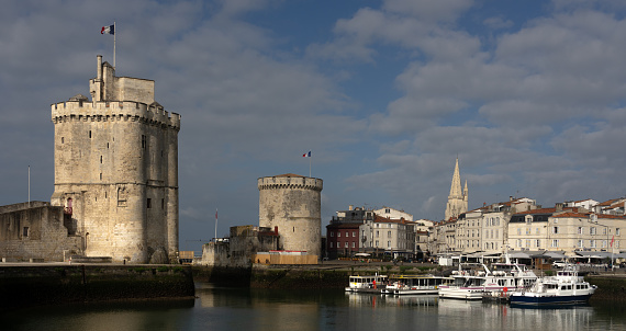 La Rochelle, France - July 01, 2023: Towers (Chaine tower and Saint Nicholas tower) of the old port of La Rochelle with a beautiful sunrise light. France.