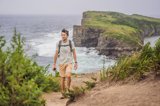 Male tourist on the background of beautiful rocks and the sea. Hiking concept. Tobizin cape. Vladivostok, island Russky. Sea of Japan. Primorye. Primorsky krai. Nature of Russia. Tourism and travel in Russia.