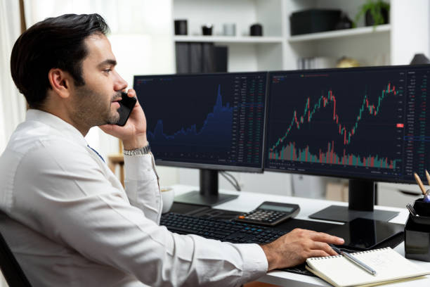 istock Trader calling to consultant or partner with two stock exchange screen. Surmise. 2085747478