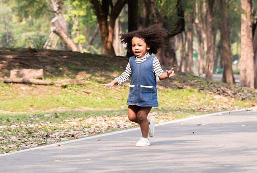 Joyful multiethnic children sprinting in a park, with windmills in hands, laughing happiness on sunny day, young school kids' friends enjoy outdoor activities running and playing together on weekend