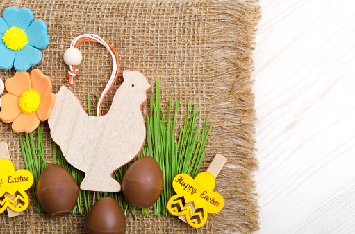 Easter chocolate eggs and green grass on a burlap background. Easter decoration. Place for text.