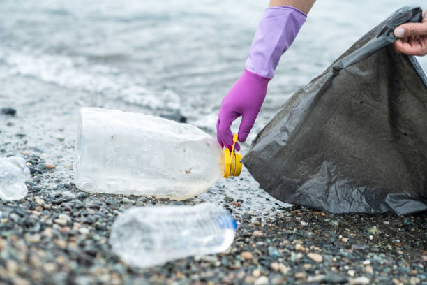 istock Man picking up plastic garbage on a beach. Plastic pollution and global ocean ecological and environment problems concept. 2085771894