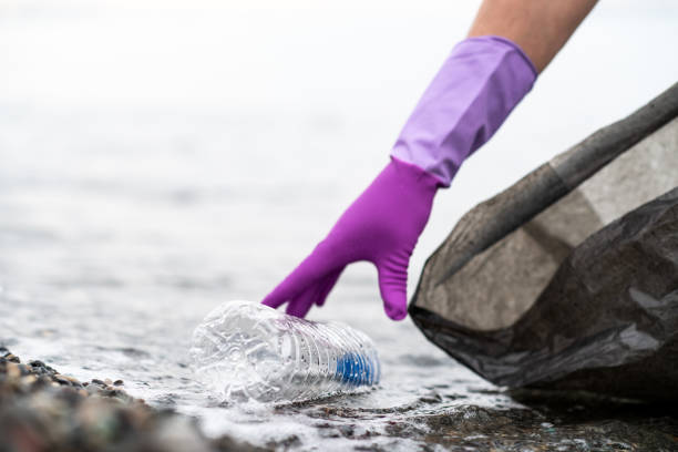 Man picking up plastic garbage on a sea shore. Plastic pollution and global ocean ecological and environment problems concept.