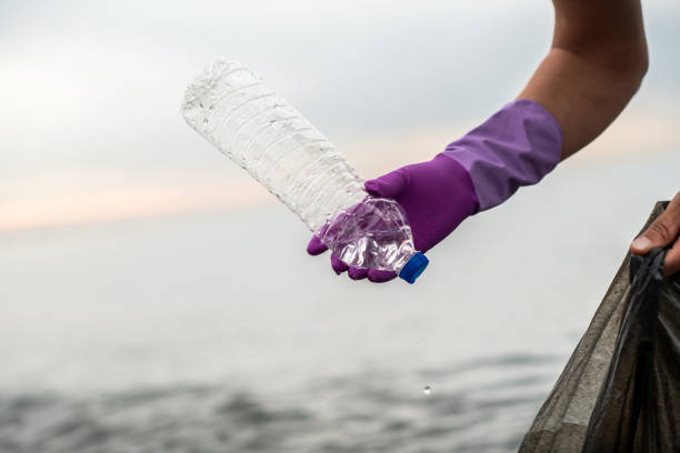 Man picking up plastic garbage on a sea shore. Plastic pollution and global ocean ecological and environment problems concept.