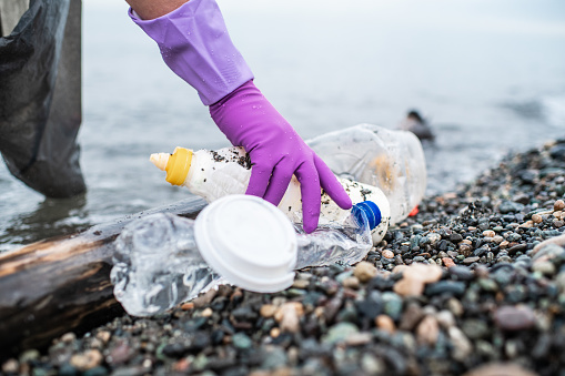 Man picking up plastic garbage on a sea shore. Plastic pollution and global ocean ecological and environment problems concept.