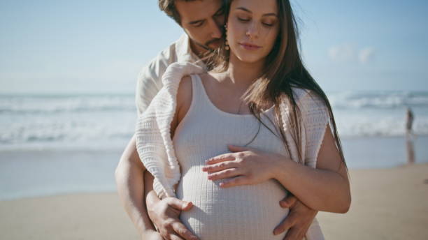 istock Affectionate pregnant couple posing on sunny beach close up. Spouses relaxing 2085774011
