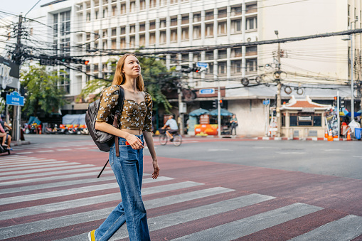 Beautiful young woman crossing the street in Chinatown in Bangkok in Thailand.