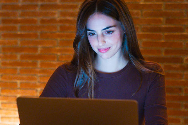 istock Portrait of young happy woman using laptop at night, using modern technology havinmg fun with glowing screen in dark office or at home, startup business meeting online with businesswoman 2085817578