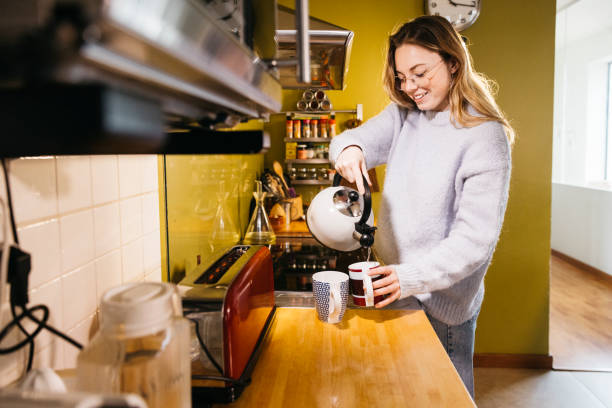 istock Young woman pouring hot water into a mug. 2085841903
