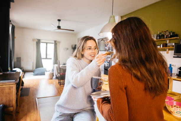 istock Young female couple eating breakfast in their home kitchen. 2085844004