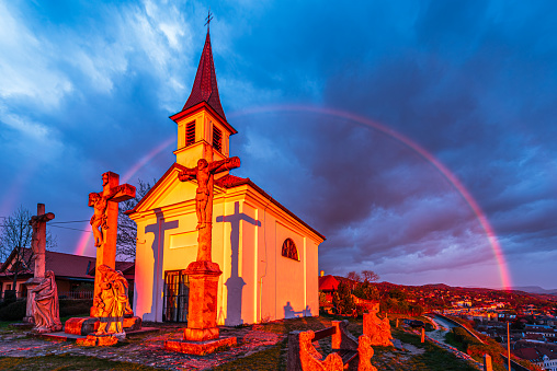 The Chapel of Saint Thomas Becket lighten by a strong sunlight with a rainbow behind in rainy clouds in Esztergom, Hungary.