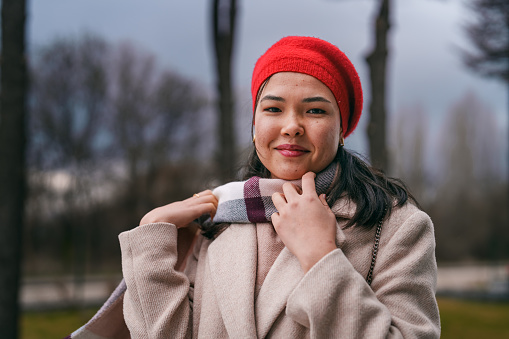 Portraits of an Asian Woman wearing a red hat and scarf.