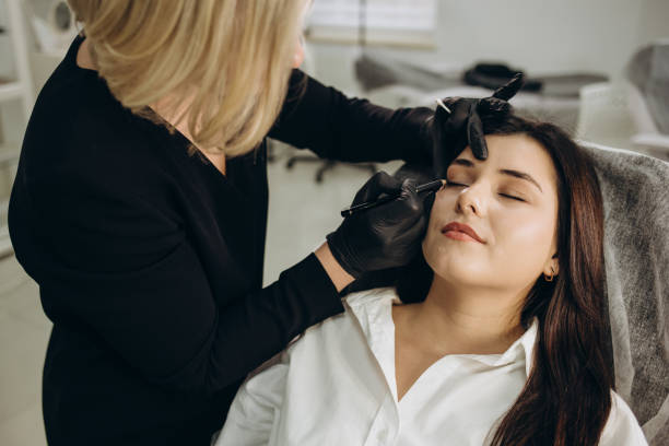 istock Permanent makeup. Eyelash Extension Procedure. Woman Eye with Long Eyelashes. Professional stylist lengthening female lashes. Eyelash extension procedure - master and a client in a beauty salon. 2085861795