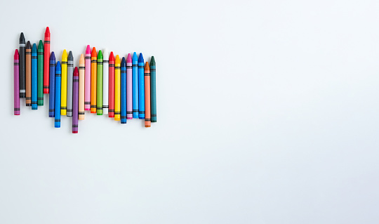 Colorful crayons sitting over blue background. Horizontal composition with copy space.