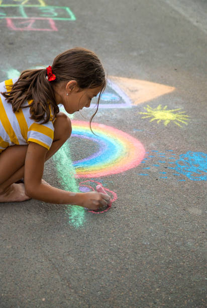 istock A child draws a house and a rainbow on the asphalt with chalk. Selective focus. 2085875179