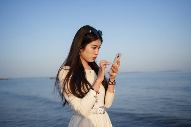 istock Girl looking at mobile phone at the beach 2085884201