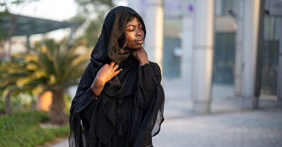 Portrait of beautiful African woman wearing black Abaya posing outdoors
