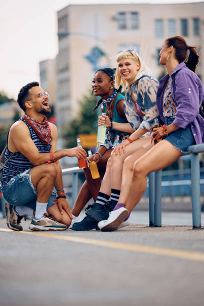 istock Carefree group of festival goers talking while relaxing on a sidewalk. 2085931072