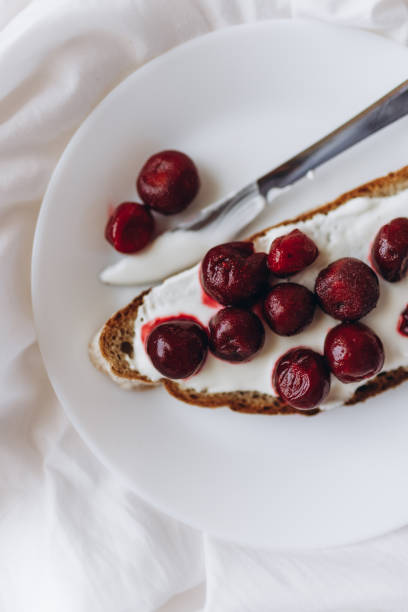 Surreal food composition of a peeled banana filled with glossy cherry tomatoes, reflecting on a white surface. Perfect for quirky food photography, healthy snack ideas, or artistic fruit displays