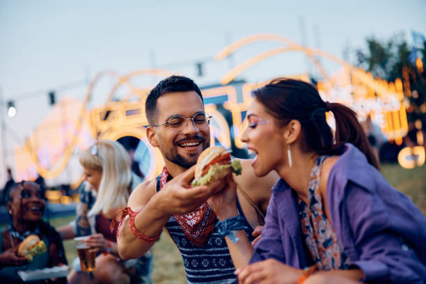 istock Happy couple sharing hamburger while attending open air music concert in summer. 2085943152
