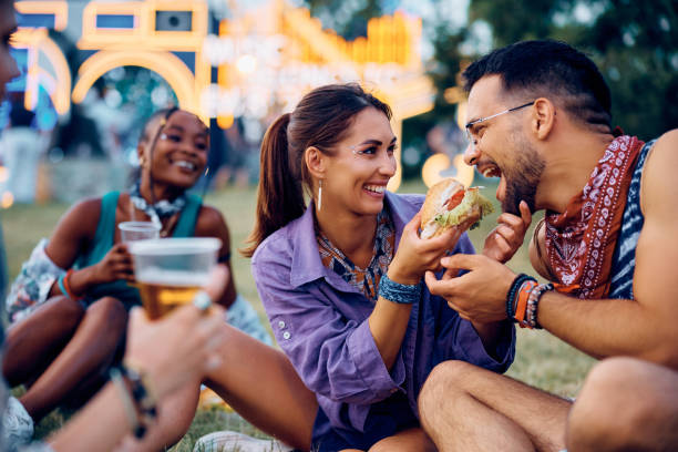 istock Happy couple having fun while sharing hamburger during open air music festival. 2085943667