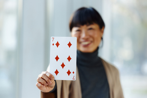 Close up of happy businesswoman holding seven of diamonds card. Copy space.