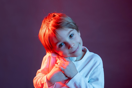 Artistic portrait of a child, boy, lightened with gel filters, studio shot