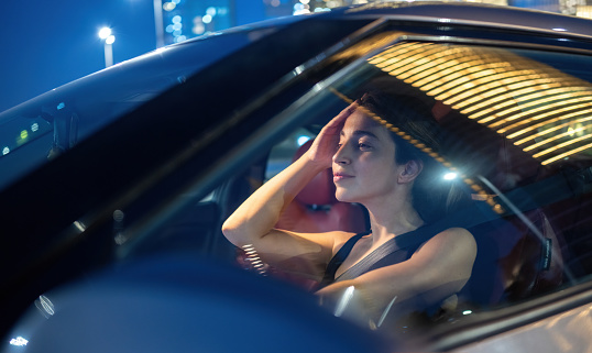 Beautiful young woman driving car at night