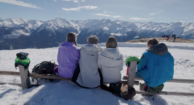 Family taking a break at ski resort in the Alps mountains on a sunny winter day