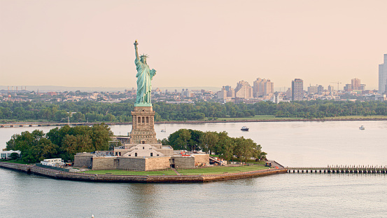 Aerial view of Statue of Liberty on Liberty Island and city at background in Lower Manhattan, New York City, New York State, USA.